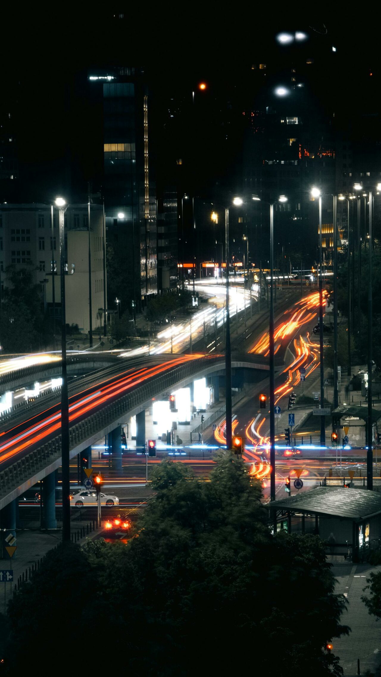 Dynamic night scene of blurred traffic lights on Warsaw's modern streets.